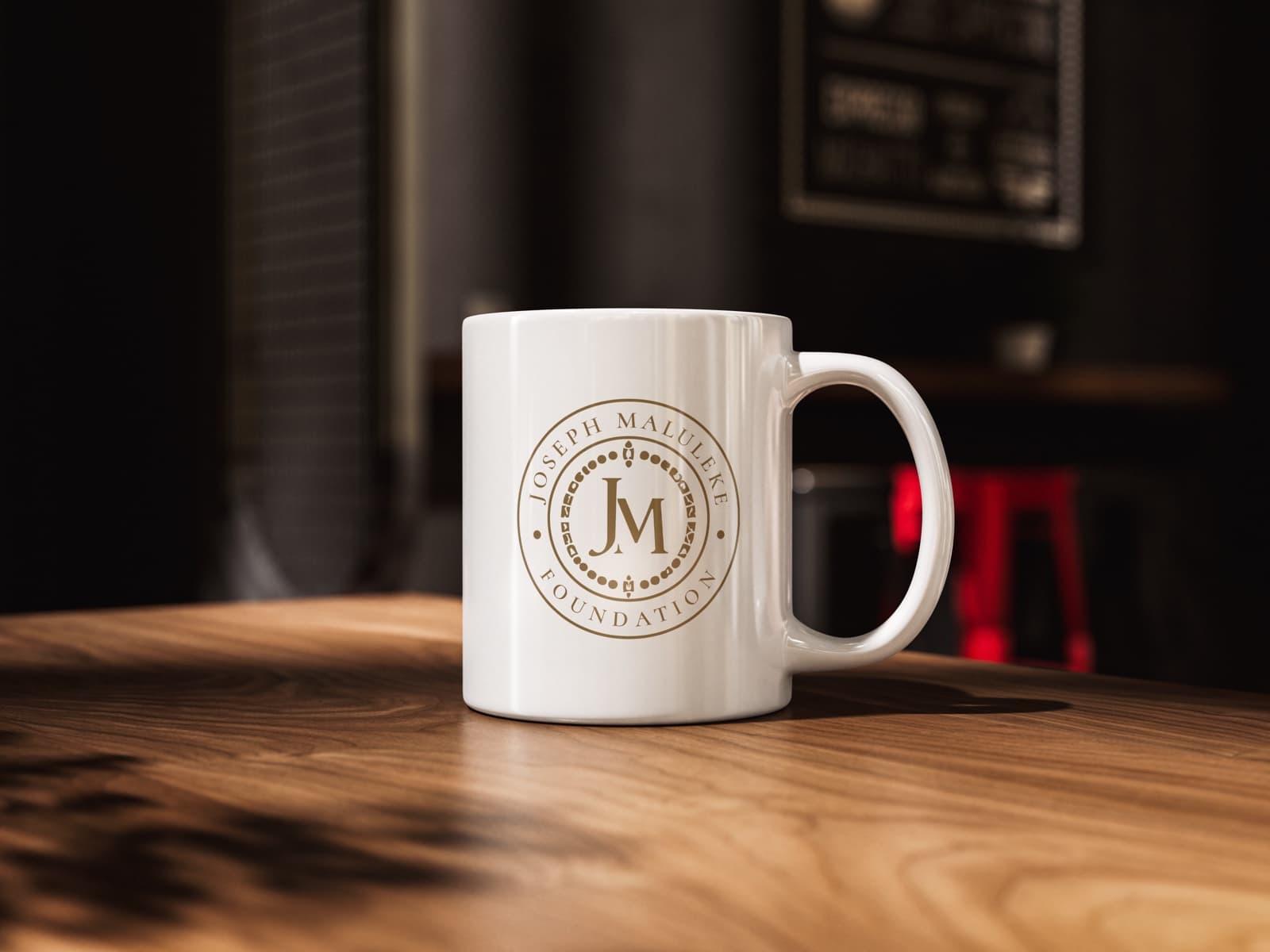 Ceramic mug with the gold circular seal in a dark cafe