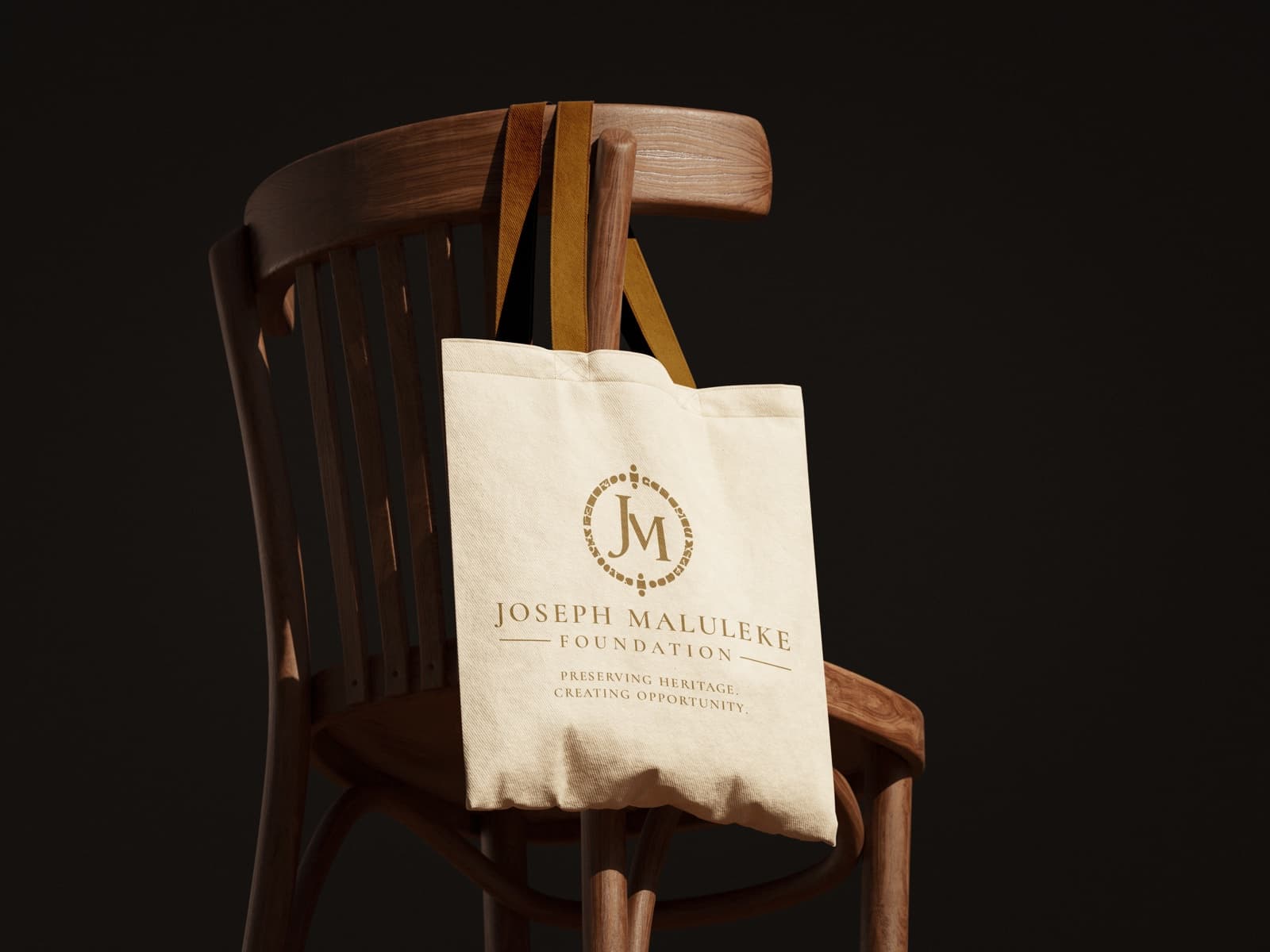 Cream tote bag with the gold foundation lockup on a bentwood chair