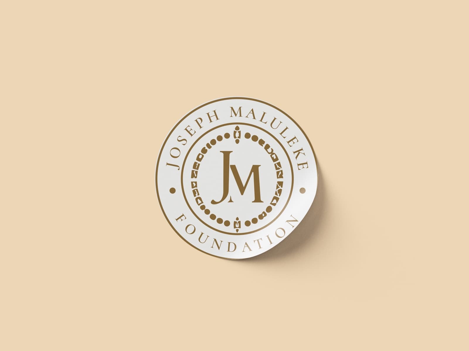 Round sticker with the full gold seal on warm sand